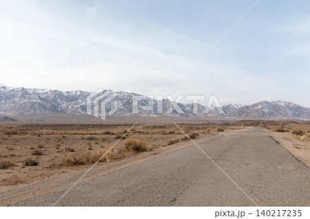 Empty asphalt road leading to snowy mountains in rural Kyrgyzstan landscape Empty asphalt road leading to snowy mountains in rural Kyrgyzstan landscape 140217235
