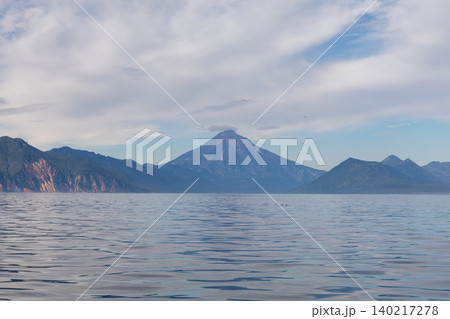 Volcano landscape over calm sea in Kamchatka with dramatic cloudy sky panorama Volcano landscape over calm sea in Kamchatka with dramatic cloudy sky panorama 140217278