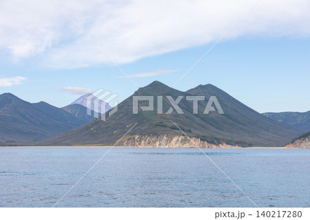 Coastal mountains and calm bay landscape in Kamchatka with volcano on horizon 140217280