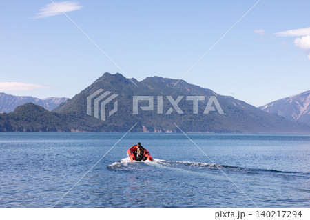 Inflatable boat heading across Avacha Bay toward mountains in Kamchatka 140217294
