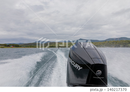 Speedboat wake on Kurilskoye Lake with volcanic mountains under cloudy sky 140217370
