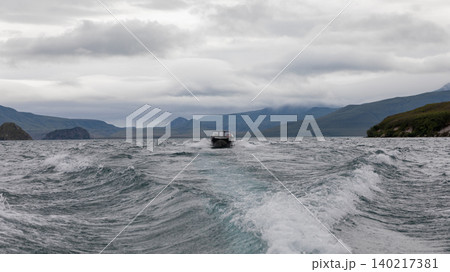 Speedboat on Kuril Lake leaving a wake under dramatic clouds, Kamchatka 140217381
