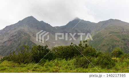 Vachkazhets mountain massif landscape with cloudy peaks and green tundra, Kamchatka Vachkazhets mountain massif landscape with cloudy peaks and green tundra, Kamchatka 140217395