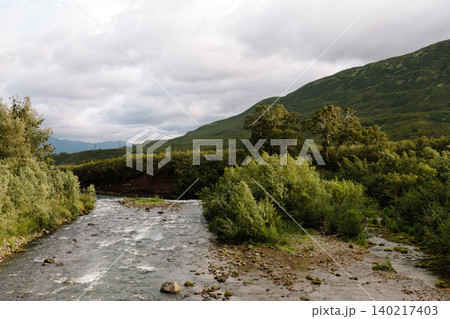 Wild river valley and green mountains in Kamchatka Peninsula, Russia under clouds Wild river valley and green mountains in Kamchatka Peninsula, Russia under clouds 140217403