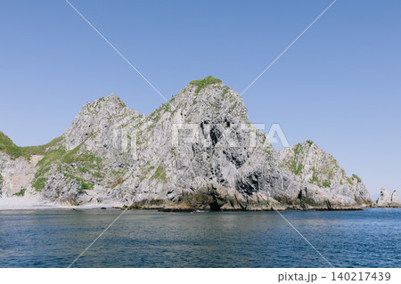 Rocky sea cliffs and green slopes on the Kamchatka Peninsula coastline, Russia Rocky sea cliffs and green slopes on the Kamchatka Peninsula coastline, Russia 140217439