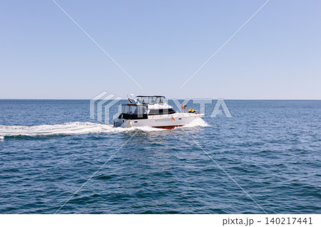 Motor yacht cruising on the Pacific Ocean near Kamchatka with wake on sunny day Motor yacht cruising on the Pacific Ocean near Kamchatka with wake on sunny day 140217441
