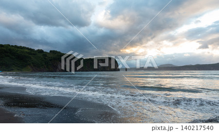 Stormy seascape with dark sand beach and coastal cliffs in Kamchatka peninsula 140217540