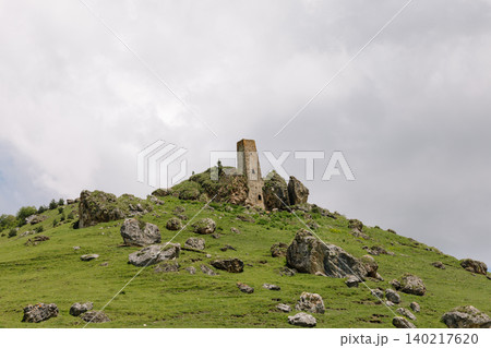 Medieval Khiani tower complex ruins on green mountain ridge under cloudy sky 140217620