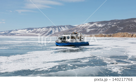 Hovercraft on frozen Lake Baikal ice with snowy mountains under blue sky Hovercraft on frozen Lake Baikal ice with snowy mountains under blue sky 140217768