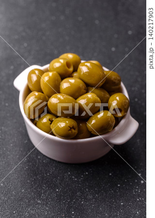 Whole green olives without pits in a bowl as an ingredient for cooking at home. Green olives Whole green olives without pits in a bowl as an ingredient for cooking at home. Green olives 140217903