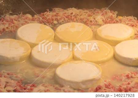 Cooking of tartiflette, a traditional French dish of scalloped potatoes, bacon and cheese, in big cauldron Cooking of tartiflette, a traditional French dish of scalloped potatoes, bacon and cheese, in big cauldron 140217928