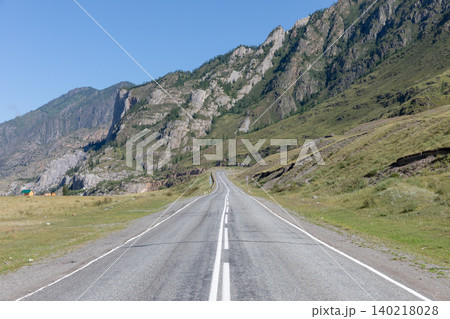 Empty highway through Altai Mountains valley with rocky cliffs and blue sky 140218028
