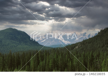 Dramatic storm clouds over Altai Mountains with sun rays and snowy peaks Dramatic storm clouds over Altai Mountains with sun rays and snowy peaks 140218035