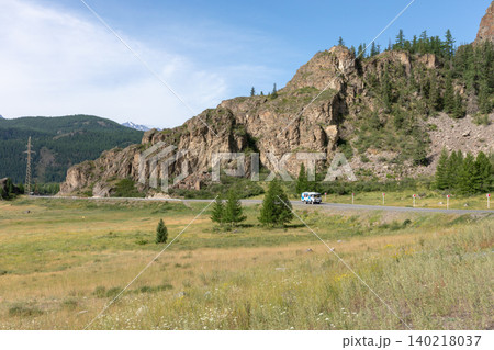 Scenic mountain road with rocky cliffs and meadow landscape in Altai region 140218037