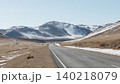 Empty highway through Tazheran steppe valley with snowy mountains, Siberia 140218079