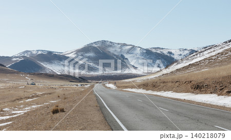 Empty highway through Tazheran steppe valley with snowy mountains, Siberia Empty highway through Tazheran steppe valley with snowy mountains, Siberia 140218079