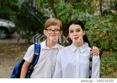 close up of teenage schoolchildren boy with glasses and a girl near a tree in the yard close up of teenage schoolchildren boy with glasses and a girl near a tree in the yard 140218105