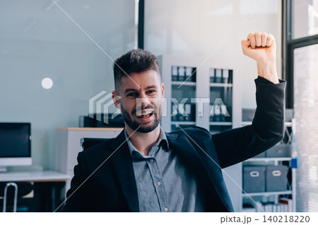 Smiling businessman in suit works on laptop in bright modern office Smiling businessman in suit works on laptop in bright modern office 140218220