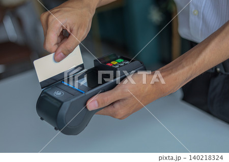 A person using a Point of Sale (POS) terminal to process a payment with a credit or debit card. 140218324