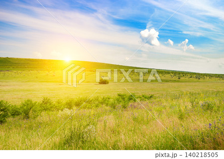 Beautiful sunrise over green hills and meadow under blue sky with clouds in summer Beautiful sunrise over green hills and meadow under blue sky with clouds in summer 140218505