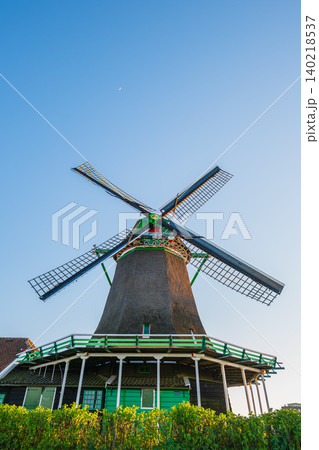 Traditional dutch windmill under clear blue sky with small crescent moon, historic wooden mill structure with copy space in zaanse schans netherlands Traditional dutch windmill under clear blue sky with small crescent moon, historic wooden mill structure with copy space in zaanse schans netherlands 140218537