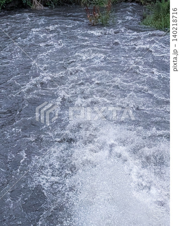 勢いよく流れる急流の川面 ／ 自然の力強さと水の躍動感を表現した背景素材 140218716