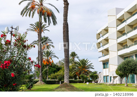 Fruiting date palm and oleander in front of a modern Mediterranean resort hotel facade with balconies in Paphos, Cyprus. Fruiting date palm and oleander in front of a modern Mediterranean resort hotel facade with balconies in Paphos, Cyprus. 140218996