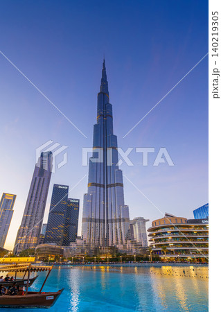 Dubai, United Arab Emirates - Jan 19 2024, vertical view of the Burj Khalifa Tower from below, with boat on foreground and dancing fountains, at evening with illumination, Dubai, UAE Dubai, United Arab Emirates - Jan 19 2024, vertical view of the Burj Khalifa Tower from below, with boat on foreground and dancing fountains, at evening with illumination, Dubai, UAE 140219305