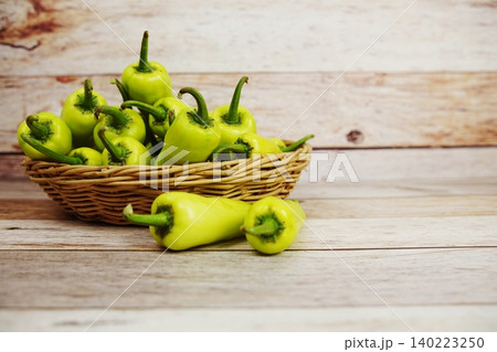 Fresh raw green bell pepper in bamboo basket on wooden background Fresh raw green bell pepper in bamboo basket on wooden background 140223250