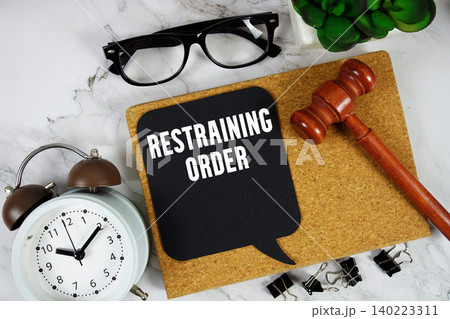 Restraining Order text on speech bubble with alarm clock and wooden gavel on marble background Restraining Order text on speech bubble with alarm clock and wooden gavel on marble background 140223311