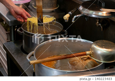 ラーメン店の厨房で平ザルを使い大鍋から麺をあげる調理シーン ラーメン店の厨房で平ザルを使い大鍋から麺をあげる調理シーン 140223483