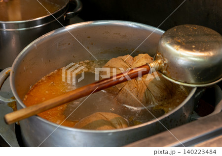 ラーメン店の寸胴鍋でだし袋を煮込む特製スープのクローズアップ 140223484