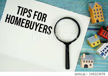 Notepad with "Tips For Homebuyers" with magnifying glass and house model on wooden background Notepad with "Tips For Homebuyers" with magnifying glass and house model on wooden background 140223676
