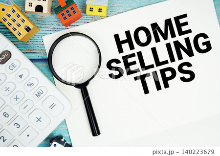 Notepad with "Home Selling Tips" with Calculator, magnifying glass and house model on wooden background Notepad with "Home Selling Tips" with Calculator, magnifying glass and house model on wooden background 140223679