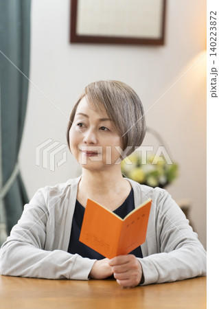 リビングで年金手帳を見るシニア女性 リビングで年金手帳を見るシニア女性 140223872