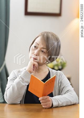 リビングで年金手帳を見るシニア女性 リビングで年金手帳を見るシニア女性 140223880