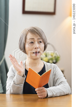 リビングで年金手帳を見るシニア女性 リビングで年金手帳を見るシニア女性 140223890