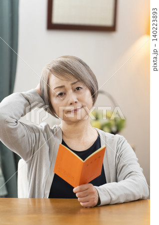 リビングで年金手帳を見るシニア女性 リビングで年金手帳を見るシニア女性 140223893