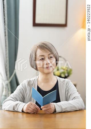 リビングで年金手帳を見るシニア女性 リビングで年金手帳を見るシニア女性 140223922