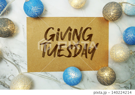 Giving Tuesday text written on paper card with LED cotton balls decorations on marble background Giving Tuesday text written on paper card with LED cotton balls decorations on marble background 140224214