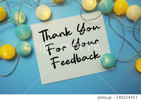 Thank You For Your Feedback text written on paper card with LED cotton balls decorations on blue background Thank You For Your Feedback text written on paper card with LED cotton balls decorations on blue background 140224451