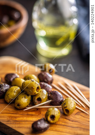 Marinated Olives On Wooden Board With Toothpicks And Olive Oil For Appetizer Platter Marinated Olives On Wooden Board With Toothpicks And Olive Oil For Appetizer Platter 140224901