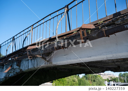 Old damaged concrete bridge in emergency condition with rusty metal railings and cracked structure Old damaged concrete bridge in emergency condition with rusty metal railings and cracked structure 140227359