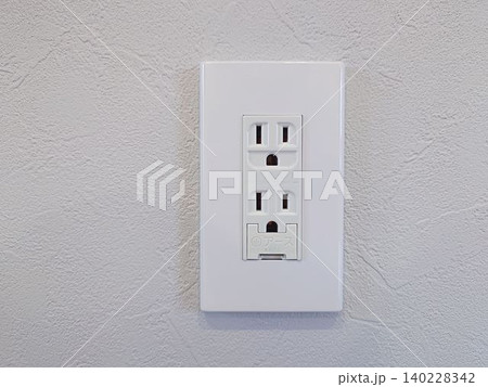 白い塗り壁に設置されたアース付き電源コンセント 白い塗り壁に設置されたアース付き電源コンセント 140228342