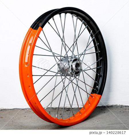 Bicolor orange and black motorcycle wheel rim in perspective view with silver spoke and hub isolated on white background for motorbike custom and repair Bicolor orange and black motorcycle wheel rim in perspective view with silver spoke and hub isolated on white background for motorbike custom and repair 140228617