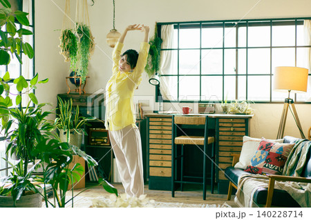 観葉植物に囲まれたリビングの窓際でストレッチをするミ若い日本人女性 観葉植物に囲まれたリビングの窓際でストレッチをするミ若い日本人女性 140228714