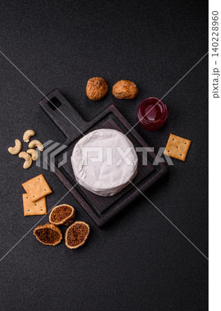 Pink Brie or Camembert cheese with honey, jam, figs, and crackers. Brie cheese 140228960