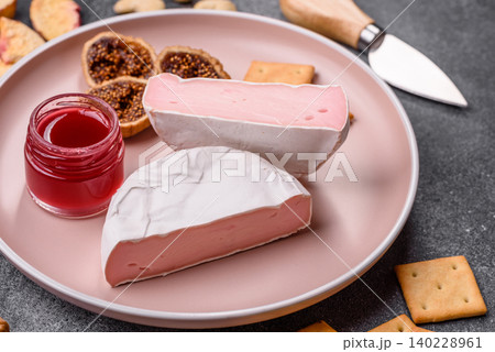 Pink Brie or Camembert cheese with honey, jam, figs, and crackers. Brie cheese 140228961