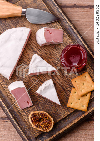 Pink Brie or Camembert cheese with honey, jam, figs, and crackers. Brie cheese 140228962