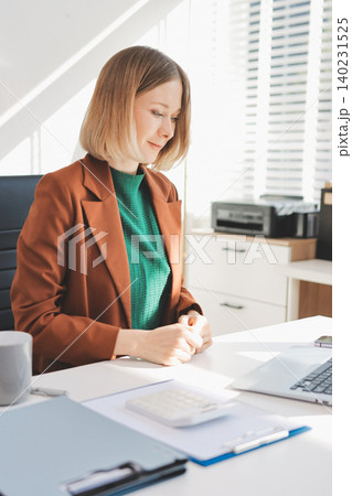 Woman smiling to herself as she works in an office 140231525